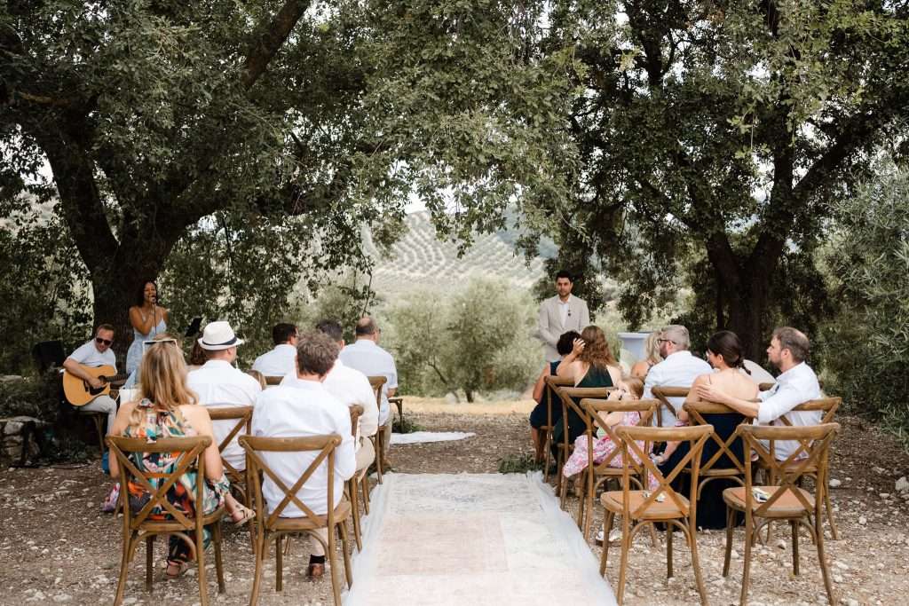 Hochzeitsgäste sitzen für eine Zeremonie im Olivenhain in Andalusien